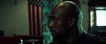 Movie still from “The Ritual Killer” (2023), directed by George Gallo – A bald man with black markings on his face; Close Up shot, Low angle