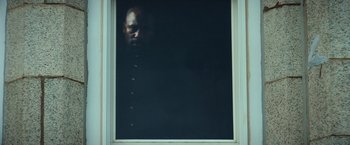 Movie still from “The Ritual Killer” (2023), directed by George Gallo – A man is looking out of a window at night; Medium shot, Low angle