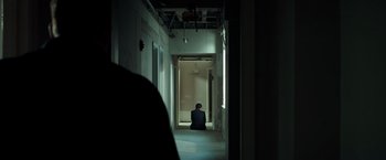 Movie still from “The Ritual Killer” (2023), directed by George Gallo – A person sitting in a hallway looking out a window; Wide shot, High angle