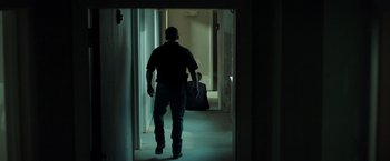 Movie still from “The Ritual Killer” (2023), directed by George Gallo – A man walking down a hallway with a suitcase; Wide shot, High angle