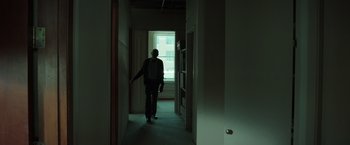 Movie still from “The Ritual Killer” (2023), directed by George Gallo – A man walking down a hallway in a building; Wide shot, Low angle