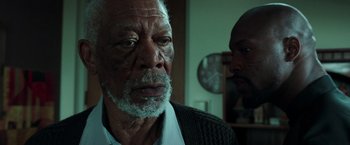 Movie still from “The Ritual Killer” (2023), directed by George Gallo – An older man is looking at the camera while a younger man looks on; Close Up shot, Over the shoulder angle