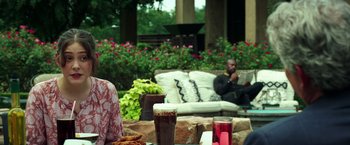 Movie still from “The Ritual Killer” (2023), directed by George Gallo – A man sitting on top of an outdoor couch; Medium shot, Over the shoulder angle