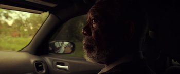 Movie still from “The Ritual Killer” (2023), directed by George Gallo – An older man sitting in the driver's seat of a car looking out the window; Close Up shot, Low angle