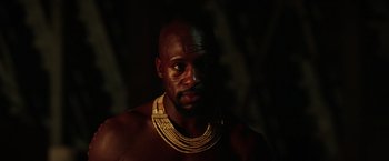 Movie still from “The Ritual Killer” (2023), directed by George Gallo – A man with a beard wearing a necklace of beads; Close Up shot, Low angle