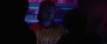 Movie still from “The Royal Hotel” (2023), directed by Kitty Green – A man with long hair is standing in a bar; Close Up shot, Over the shoulder angle