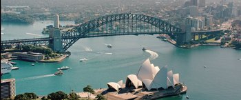 Movie still from “The Royal Hotel” (2023), directed by Kitty Green – An aerial view of the sydney opera house and the harbor bridge; Extreme Wide shot, High angle