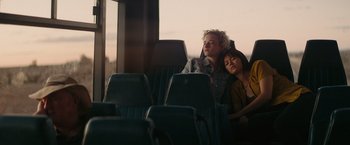 Movie still from “The Royal Hotel” (2023), directed by Kitty Green – Two people are sleeping on a seat on a bus; Medium shot, High angle