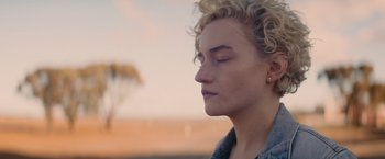 Movie still from “The Royal Hotel” (2023), directed by Kitty Green – A person with their eyes closed; Close Up shot, Over the shoulder angle