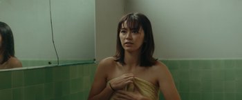 Movie still from “The Royal Hotel” (2023), directed by Kitty Green – A woman wrapped in a towel in a bathroom; Close Up shot, Over the shoulder angle