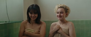 Movie still from “The Royal Hotel” (2023), directed by Kitty Green – Two young women are posing for a picture; Close Up shot, Over the shoulder angle