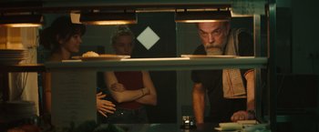 Movie still from “The Royal Hotel” (2023), directed by Kitty Green – A man and a woman looking at each other through a window; Medium shot, Low angle