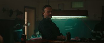 Movie still from “The Royal Hotel” (2023), directed by Kitty Green – A man standing in front of an ice chest; Medium shot, Over the shoulder angle