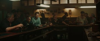 Movie still from “The Royal Hotel” (2023), directed by Kitty Green – A group of people sitting at a bar; Wide shot, Over the shoulder angle