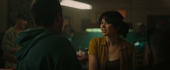 Movie still from “The Royal Hotel” (2023), directed by Kitty Green – A woman in a yellow shirt is talking to a man; Close Up shot, Over the shoulder angle