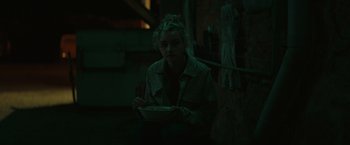 Movie still from “The Royal Hotel” (2023), directed by Kitty Green – A woman sitting down holding a bowl of food; Medium shot, High angle