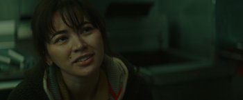 Movie still from “The Royal Hotel” (2023), directed by Kitty Green – A person smiling for the camera; Close Up shot, Over the shoulder angle