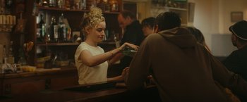 Movie still from “The Royal Hotel” (2023), directed by Kitty Green – A woman is pouring a drink into a glass; Medium shot, Over the shoulder angle