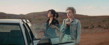 Movie still from “The Royal Hotel” (2023), directed by Kitty Green – Two young women standing in the back seat of a car; Medium shot, Over the shoulder angle