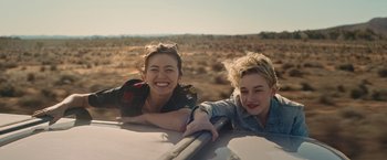 Movie still from “The Royal Hotel” (2023), directed by Kitty Green – Two young people are laying in the back of a car; Medium shot, Low angle