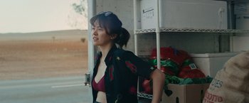 Movie still from “The Royal Hotel” (2023), directed by Kitty Green – A woman in a black shirt is standing in front of some shelves; Medium shot, Over the shoulder angle