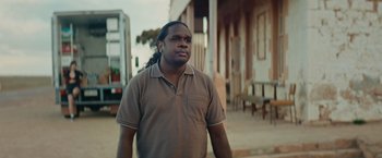 Movie still from “The Royal Hotel” (2023), directed by Kitty Green – A man standing on the side of the street; Medium shot, Over the shoulder angle