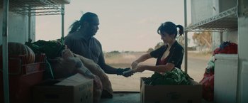 Movie still from “The Royal Hotel” (2023), directed by Kitty Green – A man and a woman are handing out food; Medium shot, Over the shoulder angle