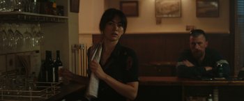 Movie still from “The Royal Hotel” (2023), directed by Kitty Green – A woman holding onto a tie in a room; Close Up shot, Over the shoulder angle