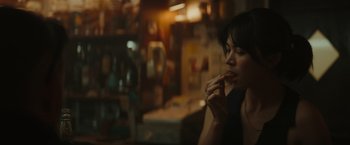 Movie still from “The Royal Hotel” (2023), directed by Kitty Green – A woman sitting at a table eating a piece of food; Close Up shot, Over the shoulder angle