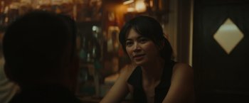 Movie still from “The Royal Hotel” (2023), directed by Kitty Green – A woman sitting at a table in front of a window; Close Up shot, Over the shoulder angle