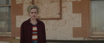 Movie still from “The Royal Hotel” (2023), directed by Kitty Green – A woman with blonde hair and a striped shirt; Medium shot, Over the shoulder angle