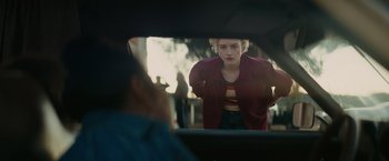 Movie still from “The Royal Hotel” (2023), directed by Kitty Green – A woman looking into a mirror while standing in a car; Medium shot, Over the shoulder angle