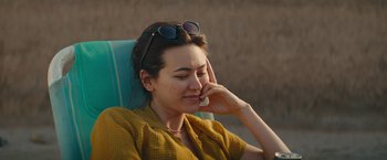 Movie still from “The Royal Hotel” (2023), directed by Kitty Green – A woman sitting in a chair with her hand on her face; Close Up shot, High angle