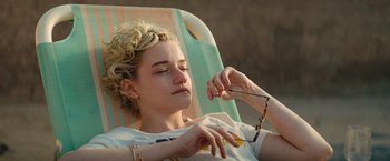 Movie still from “The Royal Hotel” (2023), directed by Kitty Green – A woman sitting in a chair with her eyes closed; Close Up shot, High angle