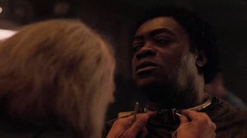 Movie still from “The Running Man” (1987), directed by Paul Michael Glaser – A man with a beard is looking at a woman with blonde hair; Close Up shot, Over the shoulder angle