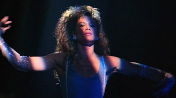 Movie still from “The Running Man” (1987), directed by Paul Michael Glaser – A woman in a blue dress with her arms outstreched; Close Up shot, Low angle