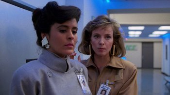 Movie still from “The Running Man” (1987), directed by Paul Michael Glaser – Two women standing next to each other in front of a blue wall; Close Up shot, Low angle