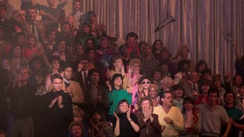 Movie still from “The Running Man” (1987), directed by Paul Michael Glaser – A group of people sitting in a room clapping; Wide shot, High angle