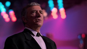 Movie still from “The Running Man” (1987), directed by Paul Michael Glaser – A person wearing a suit and tie; Close Up shot, Low angle