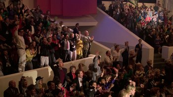 Movie still from “The Running Man” (1987), directed by Paul Michael Glaser – A group of people standing on top of a stage; Extreme Wide shot, High angle