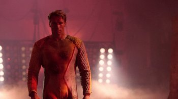 Movie still from “The Running Man” (1987), directed by Paul Michael Glaser – A man in a body suit standing in front of lights; Medium shot, Low angle