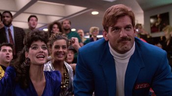Movie still from “The Running Man” (1987), directed by Paul Michael Glaser – A group of people sitting in front of an audience; Medium shot, Low angle