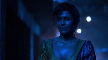 Movie still from “The Running Man” (1987), directed by Paul Michael Glaser – A woman with blue makeup standing in a dark room; Close Up shot, Low angle