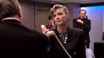 Movie still from “The Running Man” (1987), directed by Paul Michael Glaser – A woman holding a phone up to her ear; Close Up shot, Over the shoulder angle