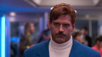 Movie still from “The Running Man” (1987), directed by Paul Michael Glaser – A man in a blue suit with a mustache; Close Up shot, Low angle