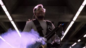 Movie still from “The Running Man” (1987), directed by Paul Michael Glaser – A man holding a gun while wearing safety glasses; Medium shot, Low angle
