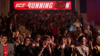 Movie still from “The Running Man” (1987), directed by Paul Michael Glaser – A group of people standing in front of an audience; Wide shot, High angle