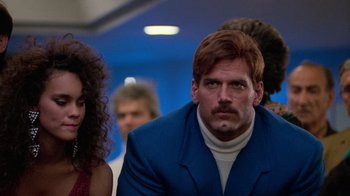 Movie still from “The Running Man” (1987), directed by Paul Michael Glaser – A man in a blue suit with a white beard; Close Up shot, Low angle