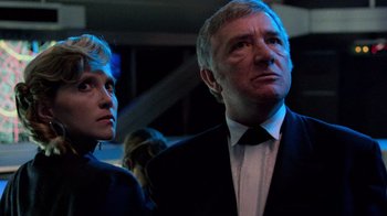 Movie still from “The Running Man” (1987), directed by Paul Michael Glaser – A man and a woman standing next to each other in a room; Close Up shot, Low angle