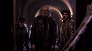 Movie still from “The Running Man” (1987), directed by Paul Michael Glaser – A group of men standing next to each other in a tunnel; Medium shot, Low angle